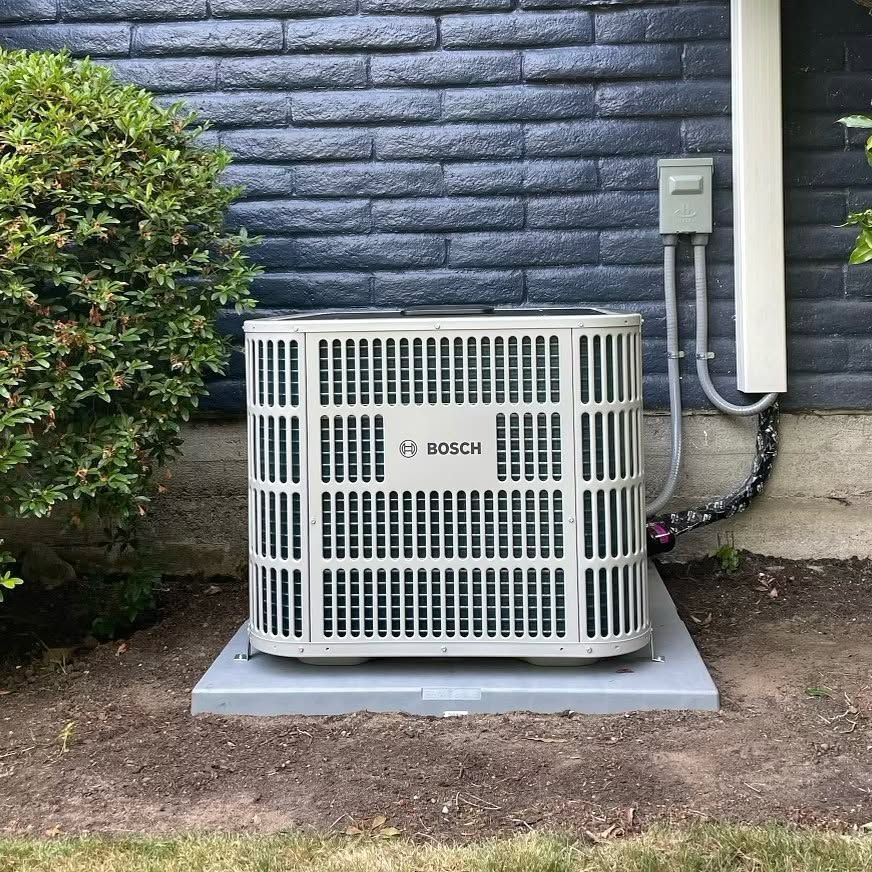Bosch heat pump installed on a new pad by a painted brick wall
