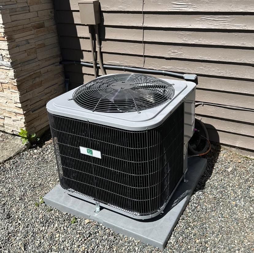 New central AC condenser on a pad in a gravel side yard
