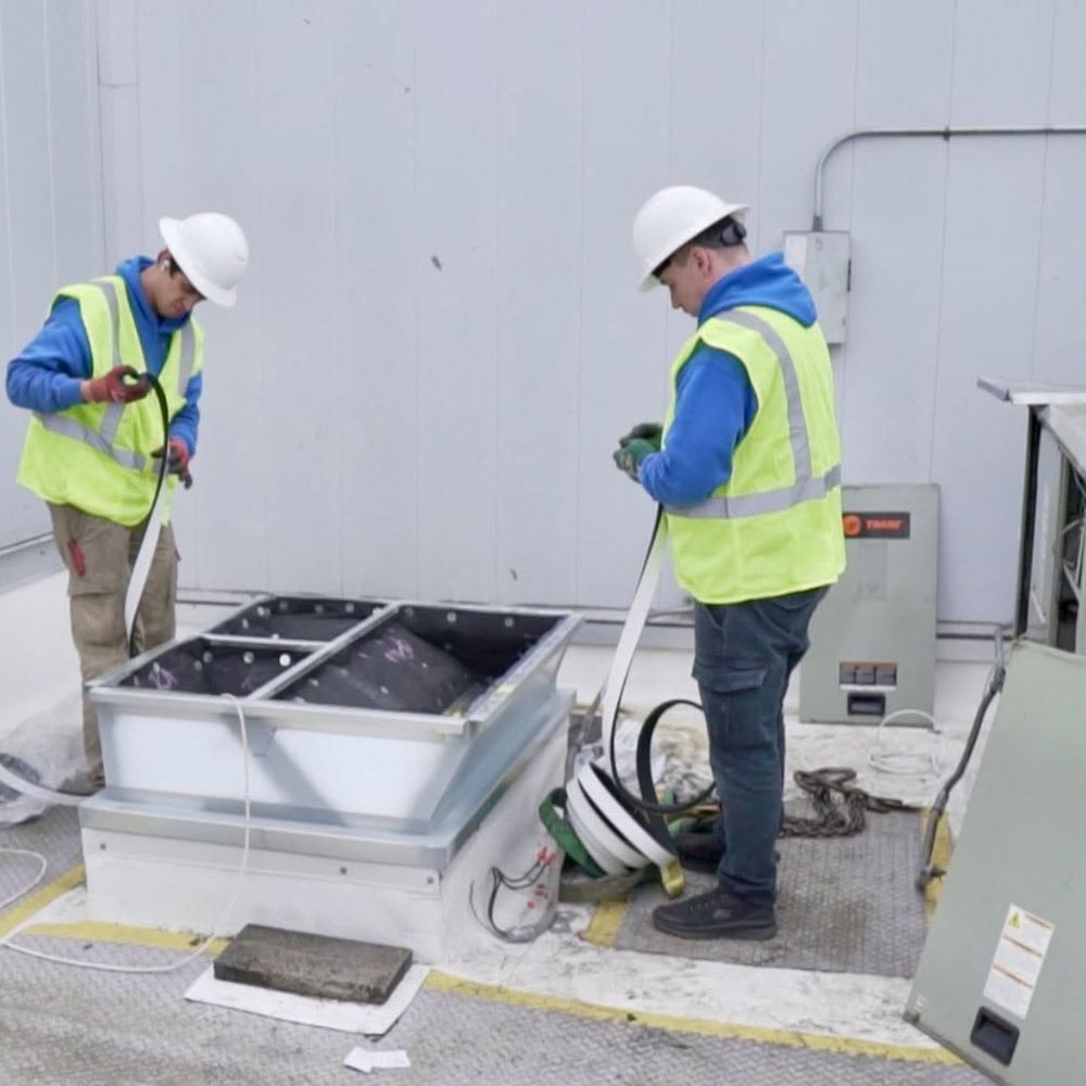 Two Seattle Heating & Cooling technicians installing rooftop equipment